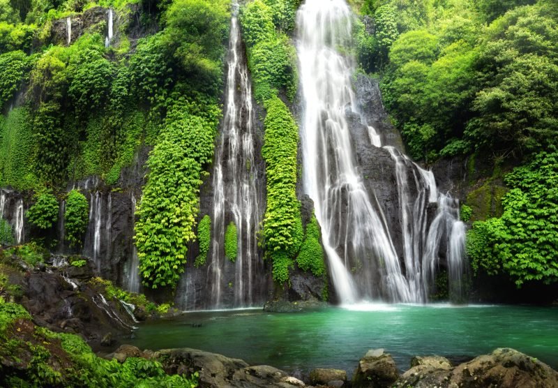 Hidden jungle waterfall cascade in tropical rainforest with rock and turquoise blue pond. Its name Banyumala because its twin waterfall in mountain slope