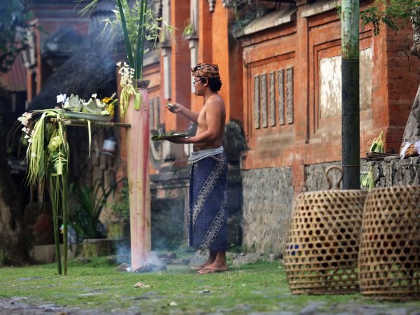 Tenganan, Indonesia - August 23, 2014: A man presents an offering for a traditional ceremony at the Tenganan Village, once one of the most secluded societies in Indonesia, it is now a tourist attraction due to its culture, architecture, and crafts. A visit is a step back in time.