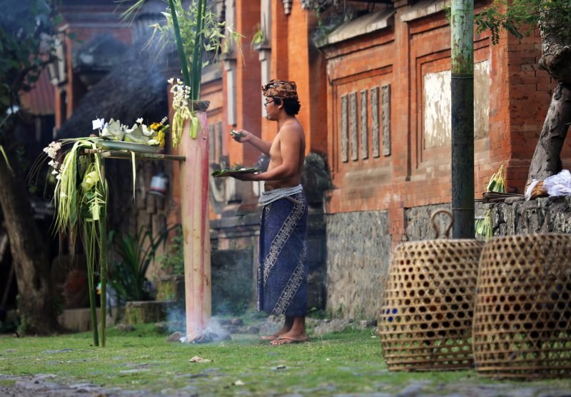 Tenganan, Indonesia - August 23, 2014: A man presents an offering for a traditional ceremony at the Tenganan Village, once one of the most secluded societies in Indonesia, it is now a tourist attraction due to its culture, architecture, and crafts. A visit is a step back in time.