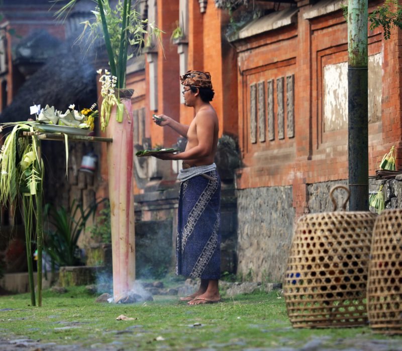 Tenganan, Indonesia - August 23, 2014: A man presents an offering for a traditional ceremony at the Tenganan Village, once one of the most secluded societies in Indonesia, it is now a tourist attraction due to its culture, architecture, and crafts. A visit is a step back in time.