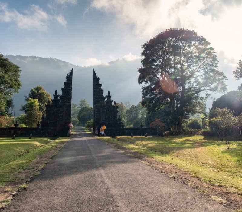 Ancient bali style gate with pathway and shining on tree