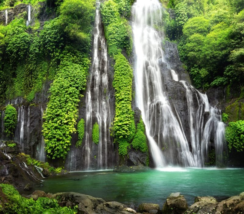 Hidden jungle waterfall cascade in tropical rainforest with rock and turquoise blue pond. Its name Banyumala because its twin waterfall in mountain slope