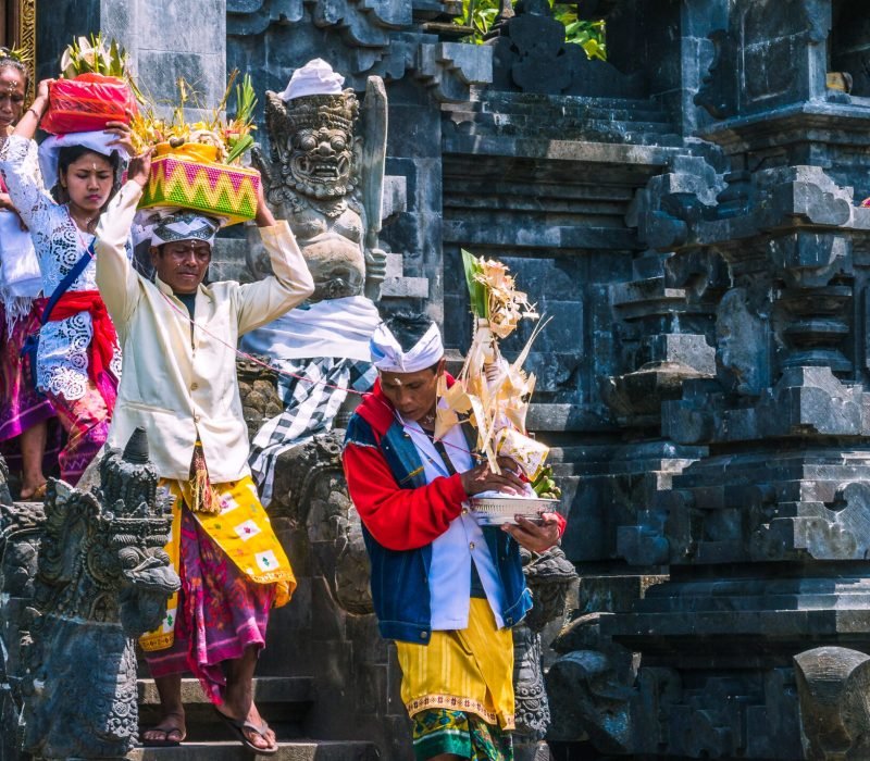 GOA LAWAH, BALI, INDONESIA - November 3, 2016: Balinese people in traditional clothes carry bless gift after ceremony at Pura Goa Lawah temple, Bali, Indonesia.
